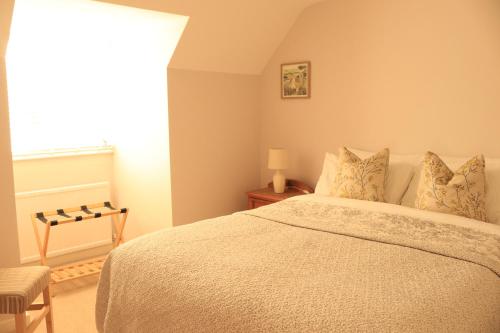 a bedroom with a bed and a chair and a window at Beautiful Cottage in the Heart of Stow on the Wold in Stow on the Wold