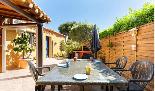 ル・バルカレスにあるMagnifique Maison avec piscine privée à 300 m d'une trés jolie plage de sableのテーブルと椅子と傘のあるパティオ