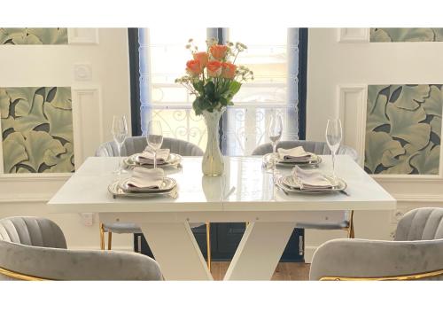une table blanche avec des chaises et un vase de fleurs dans l'établissement Villa Sérénité appartement au centre ville n 5, à Lourdes