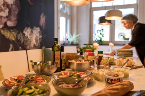 a table with bowls of food and a woman preparing food at VillaEnzo - ELEGANT HERENHUIS - 14P - 6SLPK - SAUNA - INFRAR CABINE - OFYR BBQ - 15MIN Maastricht in Zussen