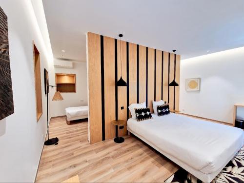 a bedroom with a large white bed with black pillows at Hôtel Le Mistral in Porto-Vecchio