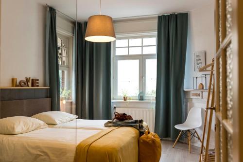 a bedroom with a bed and a window with green curtains at VillaEnzo - ELEGANT HERENHUIS - 14P - 6SLPK - SAUNA - INFRAR CABINE - OFYR BBQ - 15MIN Maastricht in Zussen