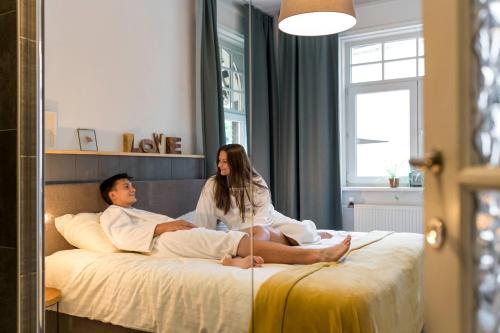 a man and a woman sitting on a bed at VillaEnzo - ELEGANT HERENHUIS - 14P - 6SLPK - SAUNA - INFRAR CABINE - OFYR BBQ - 15MIN Maastricht in Zussen