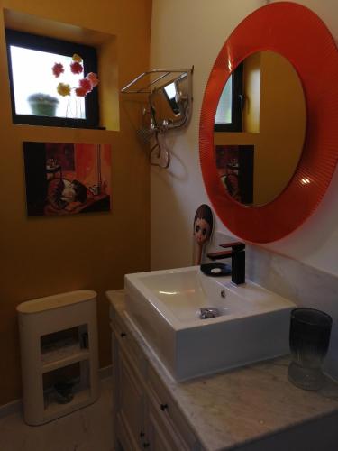 a bathroom with a white sink and a red mirror at Maison d'Art' lette in Saint-Féliu-dʼAvall