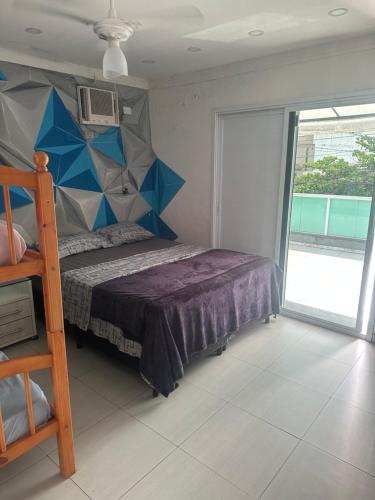 a bedroom with a bed with a blue and gray headboard at Sol & Mar Hostel in Praia Grande