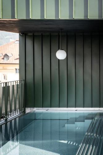 a swimming pool with a green wall and a pendant light at ADLER Historic Guesthouse in Bressanone