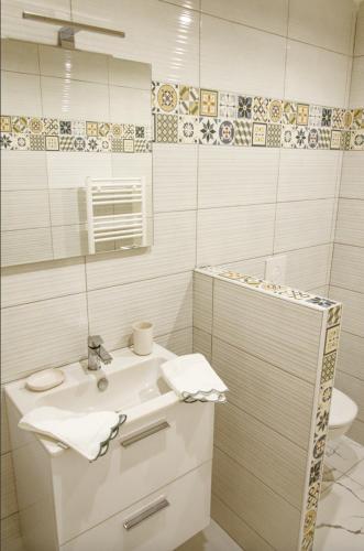 ein weißes Badezimmer mit einem Waschbecken und einem Spiegel in der Unterkunft Le St Apollinaire n°3 - Ma Cabotte in Meximieux