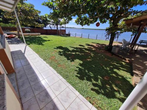 a grassy yard with a tree and the water at LINDO SOBRADO COM 7 QUARTOS NA BARRA DO ITAPOCU in Paraty