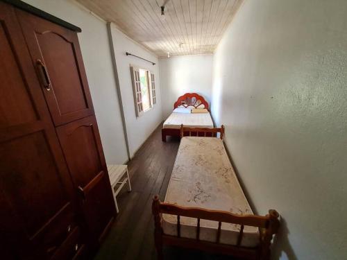 a small room with two beds and a door at LINDO SOBRADO COM 7 QUARTOS NA BARRA DO ITAPOCU in Paraty