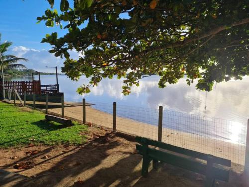 a park bench next to a fence next to the water at LINDO SOBRADO COM 7 QUARTOS NA BARRA DO ITAPOCU in Paraty