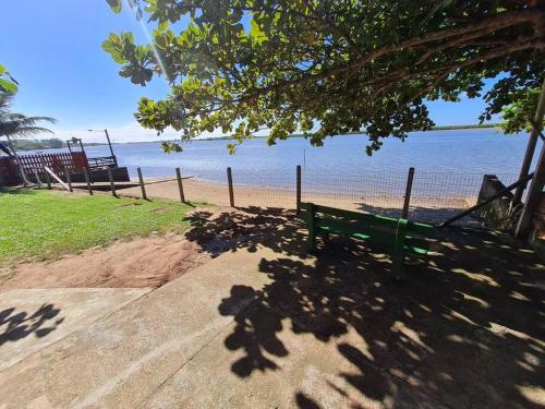 a green park bench sitting on the beach at LINDO SOBRADO COM 7 QUARTOS NA BARRA DO ITAPOCU in Paraty