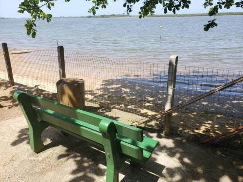 a green bench sitting next to a body of water at LINDO SOBRADO COM 7 QUARTOS NA BARRA DO ITAPOCU in Paraty