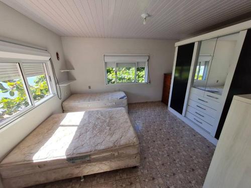 a bedroom with two beds and two windows at LINDO SOBRADO COM 7 QUARTOS NA BARRA DO ITAPOCU in Paraty