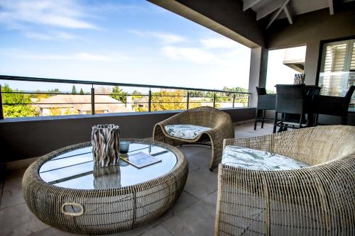 a patio with a table and chairs and a balcony at Selkirk House in Hermanus