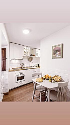 a white kitchen with a table and a table and chairs at La casa de mis suegros in Candeleda