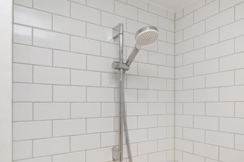 a shower head in a bathroom with white tiles at Come Stay 50 meter til vand, plads til 6-personer in Aarhus