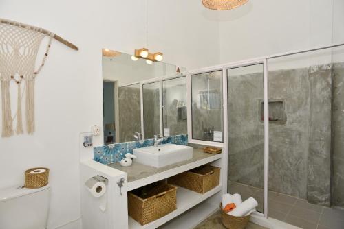 La salle de bains blanche est pourvue d'un lavabo et d'une douche. dans l'établissement Rodrigues Holiday Family Villa Zourit, à Rodrigues Island