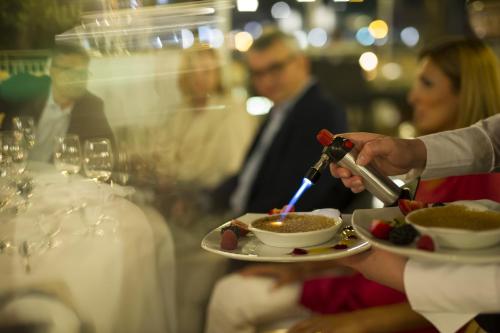 a person lighting a candle on a plate of food at Insel-Hotel Heilbronn in Heilbronn