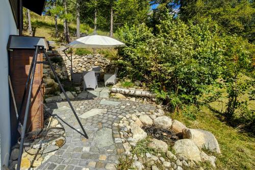 a patio with an umbrella and a stone pathway at Chalet Bijou in Blitzingen