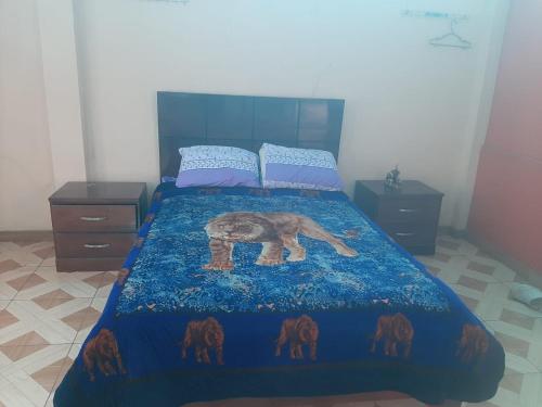 Un dormitorio con una cama con una manta azul con un elefante. en CUARTO TINGALES en Tingo María