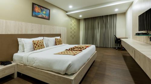 a bedroom with a large bed and a desk at Monk's Nirvanaa Hotel & Resort in Indore