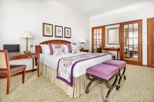 a bedroom with a bed and a desk and a computer at Palácio Estoril Hotel, Golf & Wellness in Estoril