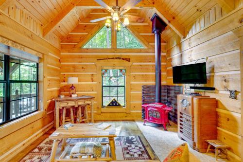 a log cabin living room with a tv and a table at Cozy Log Cabin on 11 Acres 3 Mi to Cherokee Lake! in Bean Station