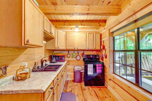 a kitchen with wooden cabinets and a sink and a stove at Cozy Log Cabin on 11 Acres 3 Mi to Cherokee Lake! in Bean Station