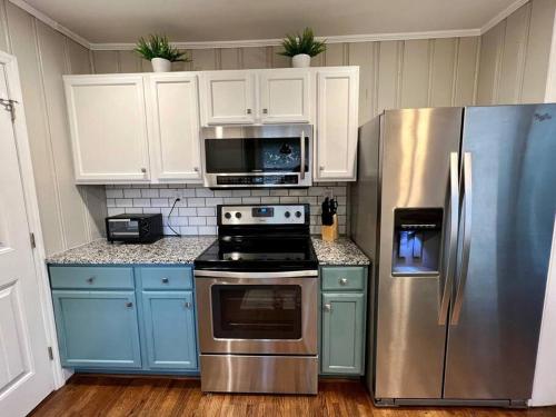 La cuisine est équipée de placards bleus et d'un réfrigérateur en acier inoxydable. dans l'établissement The Mockingbird Nest, à Charlotte