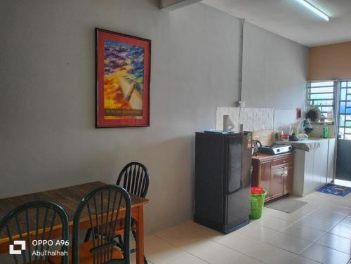 eine Küche mit einem Esstisch und eine Küche mit einem Kühlschrank in der Unterkunft Homestay Saujana Harmoni D'Petron in Gua Musang