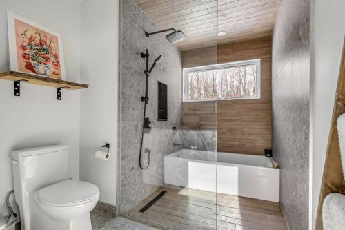 a bathroom with a toilet and a bath tub at Le Gaïa - Chalet en nature in Quebec City