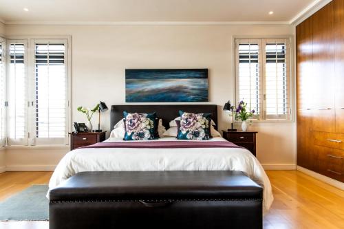 a bedroom with a large bed with a black ottoman at Selkirk House in Hermanus