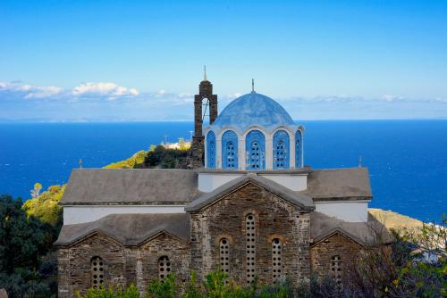 an old church with a tower on top of the ocean at Endless green 1 Arethousa Ikaria in Arethousa