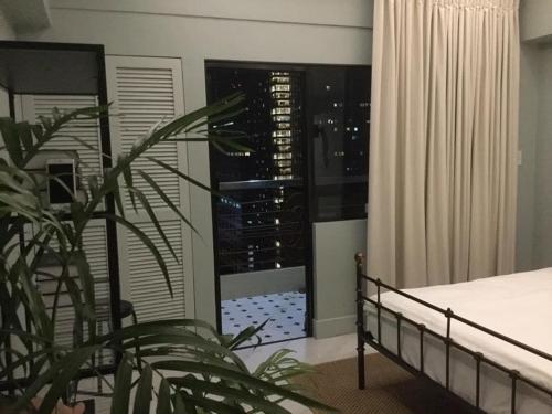 a bedroom with a bed and a window with a plant at Condo Hotel at Greenbelt makati with cityview in Manila