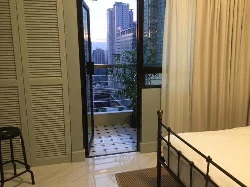 a bedroom with a balcony with a view of a city at Condo Hotel at Greenbelt makati with cityview in Manila