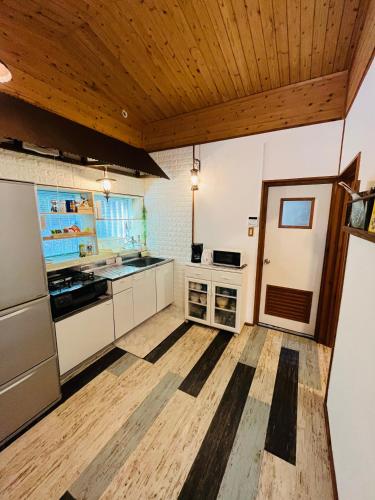 a kitchen with white cabinets and a wooden ceiling at Lodge Crea in Ujimi