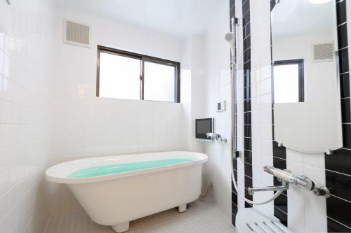 a bath tub in a white bathroom with a window at NAOMI - Self Check-In Only in Osaka