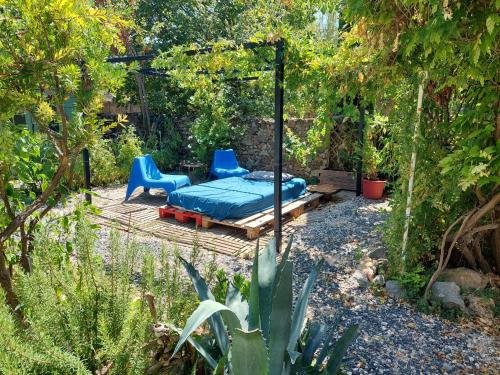 a patio with a bed and a bench in a garden at Chambres d'hôtes : Les maisons de Gaïa in Tuchan