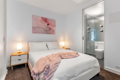 een witte slaapkamer met een bed en een badkamer bij Cozy & Romantic 1 Bedroom Apt in Southbank with Pool & Gym in Melbourne