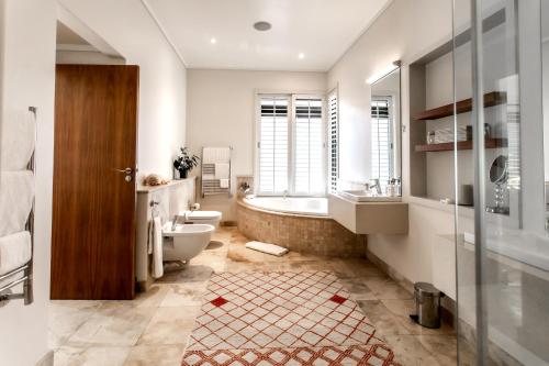 a bathroom with a tub and a toilet and a sink at Selkirk House in Hermanus