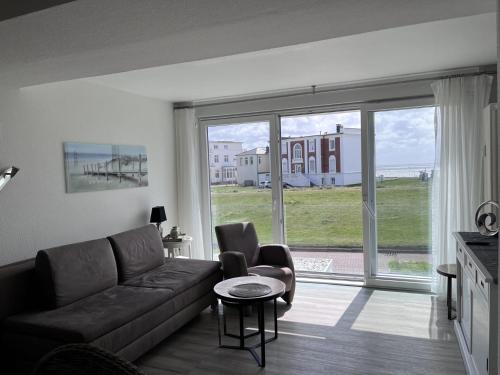 un soggiorno con divano, sedie e una grande finestra di Seelord 16 a Norderney