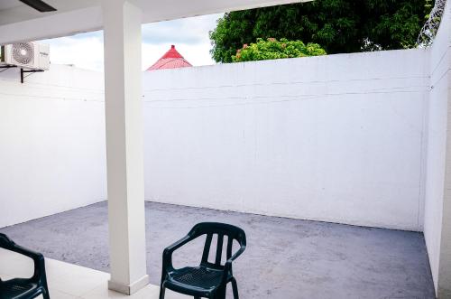 two black chairs sitting on a porch with a white wall at Hermosa casa en Costa de Oro in Montería