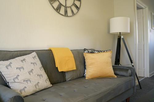 ein Sofa mit Kissen und eine Uhr an der Wand in der Unterkunft McCracken House in Uddingston