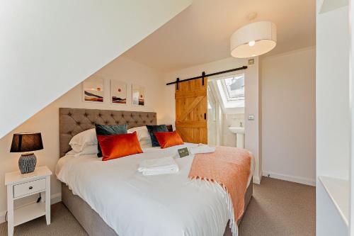 um quarto com uma cama grande e almofadas laranja em 18 - 3 Bedroom Cottage - LP em Pwllheli