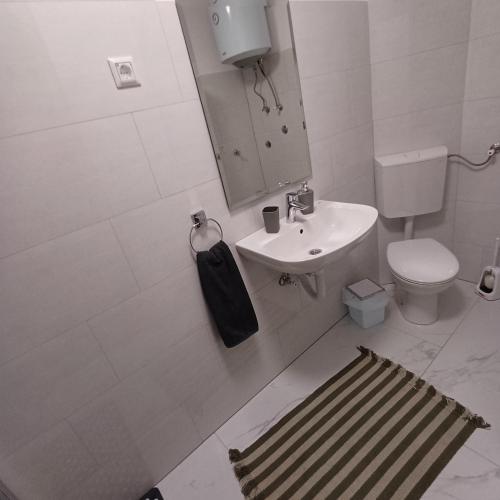 a white bathroom with a sink and a toilet at Rose Apartment in Jajce