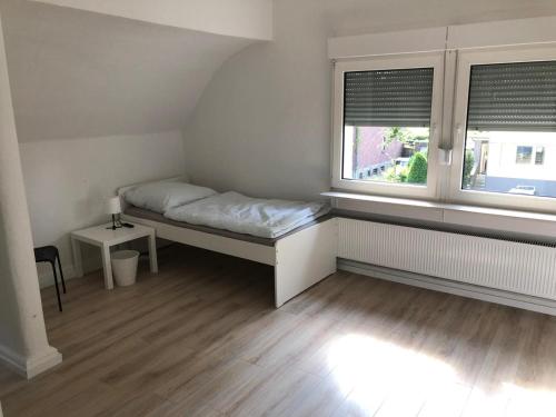 a small bedroom with a bed and two windows at Work & Stay Apartments in Selm-Bork in Selm