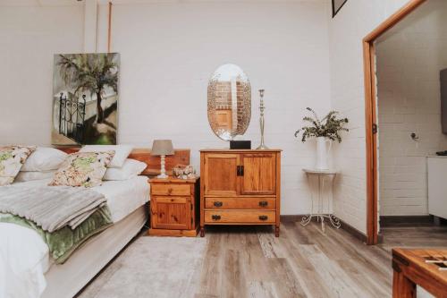 a bedroom with a bed and a dresser with a mirror at Upington African Vineyard Boutique Hotel & SPA in Kanoneiland