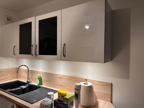 eine Küche mit weißen Schränken und einem Waschbecken in der Unterkunft Colombes Proche La Défense et Paris, 1 chambre, SDB, wifi et cuisine équipée in Colombes