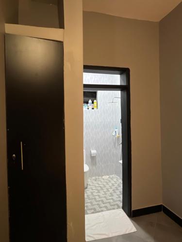 a bathroom with a toilet and a black door at Fivas Residences in Arua