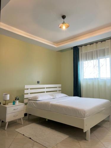 a bedroom with a white bed and a window at Fivas Residences in Arua